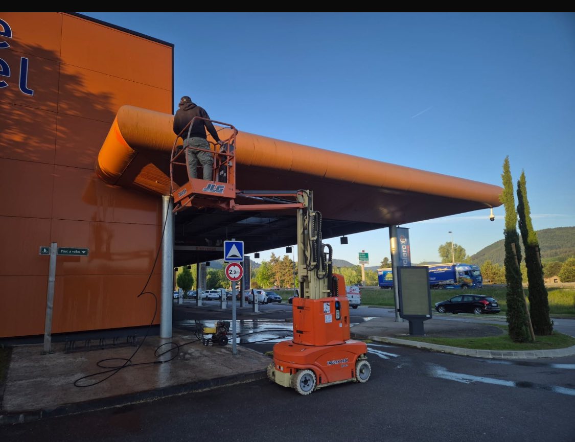 Nettoyage et traitement de façade Un professionnel nettoie la façade extérieure d’un bâtiment à l’aide d’une nacelle élévatrice.