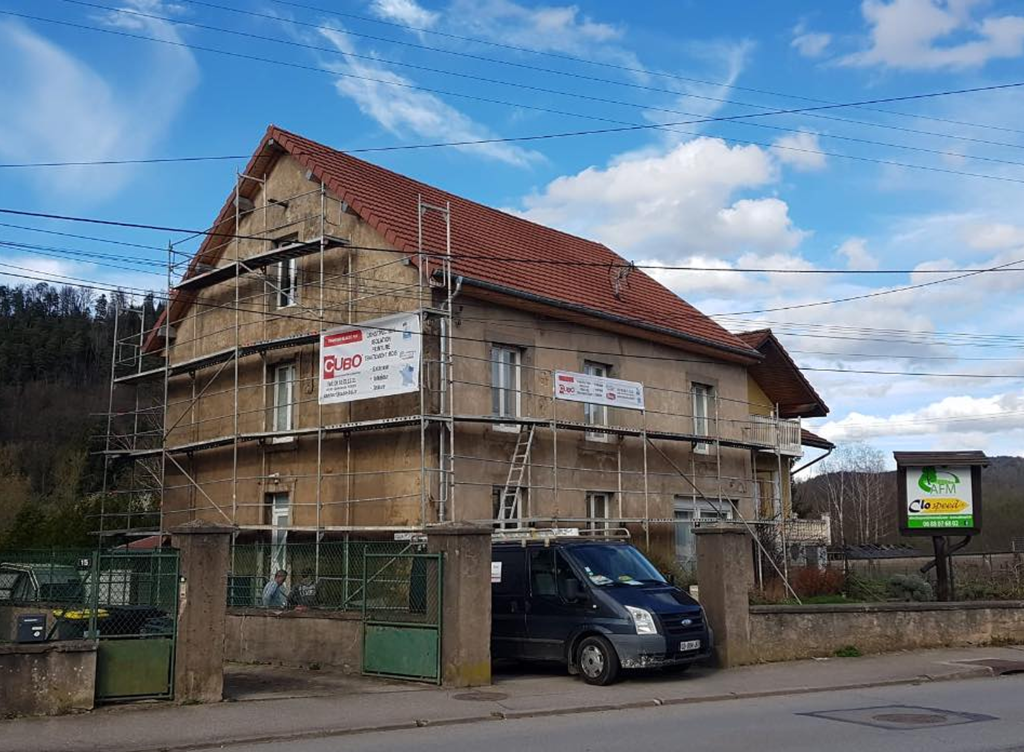 Chantier de rénovation de façade – CUBO EST Maison en cours de rénovation avec échafaudages et panneau CUBO EST visible sur la façade, avant isolation et ravalement.