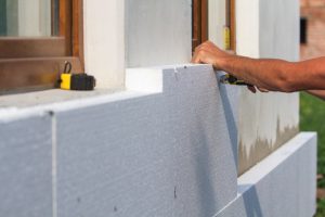 Pose d’un isolant thermique extérieur Installation d’un isolant thermique en polystyrène expansé sur la façade d’une maison.